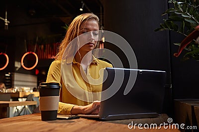 young attractive blond cauasian woman sitting at coffe shop, working on laptop Stock Photo