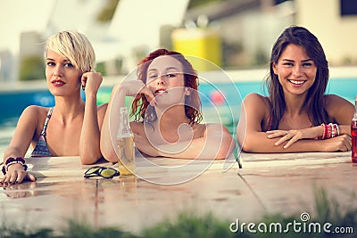Blond, brunette and red haired female bathers posing on edge of Stock Photo