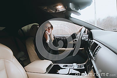 Young attractive blonde uses phone while sitting in car. Lifestyle and cars Stock Photo