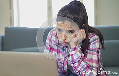 Young attractive and bored latin woman on her 30s working at home living room sitting on couch with laptop computer in stress look Stock Photo