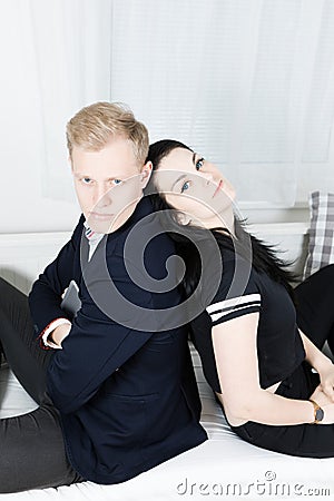 Young attractive business colleagues in love - sitting on bed back to back Stock Photo