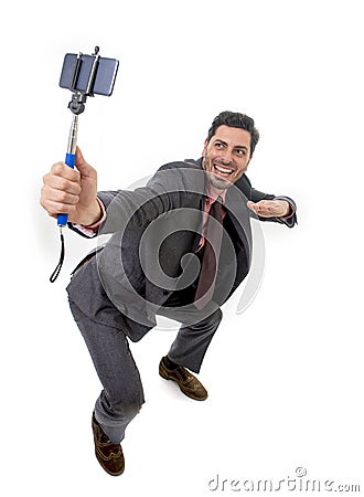 Young attractive businessman in suit and tie taking selfie photo with mobile phone camera and stick posing happy Stock Photo