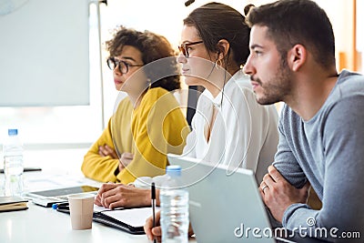 Young attractive businesspeople paying attention in conference on coworking place Stock Photo