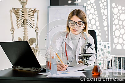 Young attractive Caucasian woman scientist in white coat and eyeglasses in the scientific medical chemical laboratory Stock Photo