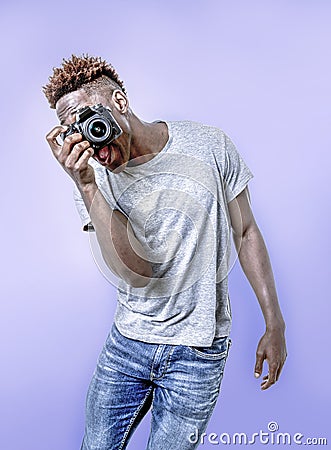 Young attractive and cool happy black afro American man holding digital reflex photo camera smiling excited background Stock Photo