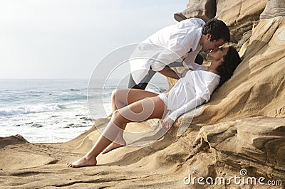 Young attractive couple sharing a moment outdoors on beach rocks Stock Photo