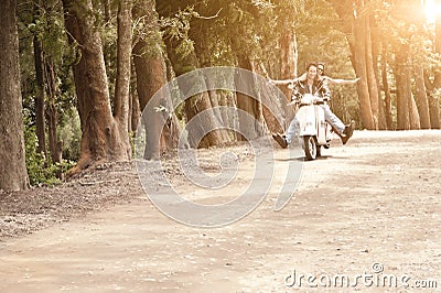 Young attractive couple traveling on scooter along dirt road Stock Photo