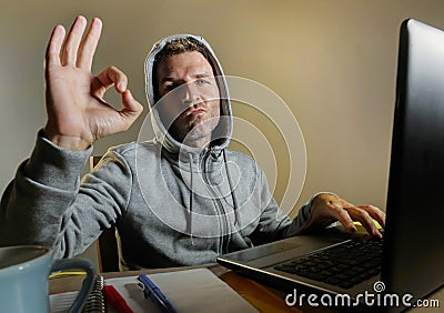 Young attractive and dangerous looking hacker computer geek working on laptop computer hacking or protecting vulnerable system giv Stock Photo