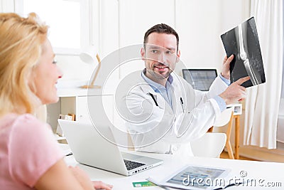 Young attractive doctor analysing X-ray with patient Stock Photo