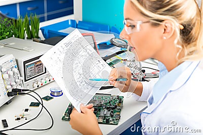 Female electronic engineer checking electronic circuit in laboratory Stock Photo