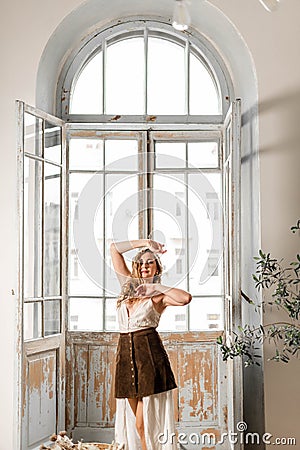 Young attractive girl in a dress in front of a large balcony window Stock Photo