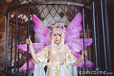 Young attractive girl dressed as fairy in the cage Stock Photo