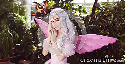 Young attractive girl dressed as fairy in green garden Stock Photo