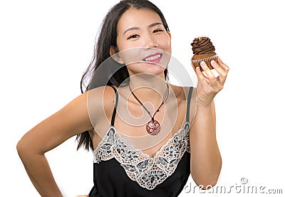Young attractive and happy Asian Chinese woman holding delicious and tempting chocolate cupcake full of calories having dilemma Stock Photo