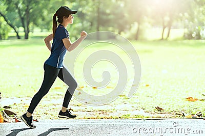 Young attractive happy asian runner woman running in public nature city park wearing sporty sportswear with copy space and sun lig Stock Photo