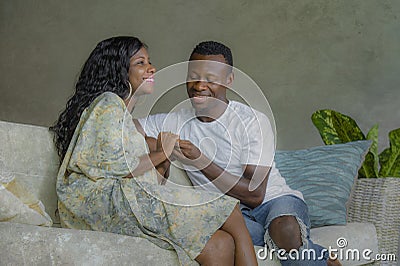 Young attractive and happy black African American couple relaxed at home sofa couch talking sweet enjoying together and smiling in Stock Photo