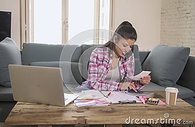 Young attractive and happy hispanic woman checking bills bank papers expenses and monthly payments smiling at apartment living roo Stock Photo