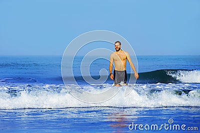 Young attractive and happy man with beard and swimming trunks at tropical paradise desert beach alone playful and cheerful in sea Stock Photo