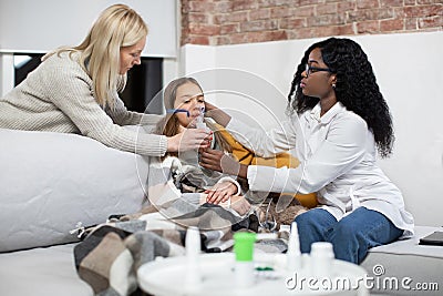 Young attractive high-skilled African lady doctor helping caring mother to put on her sick daughter& x27;s face nebulizer Stock Photo