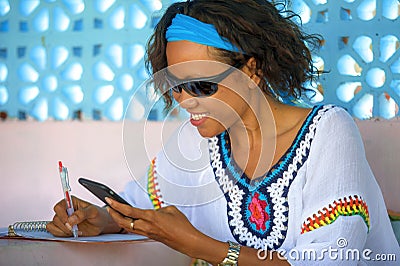 Young attractive hipster and exotic looking girl happy and relaxed using internet social media working on mobile phone smiling tak Stock Photo