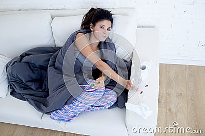 Young attractive hispanic woman lying sick at home couch in cold and flu in gripe disease symptom Stock Photo