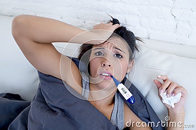 Young attractive hispanic woman lying sick at home couch in cold and flu in gripe disease symptom Stock Photo