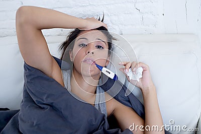 Young attractive hispanic woman lying sick at home couch in cold and flu in gripe disease symptom Stock Photo