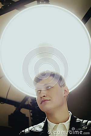 Young attractive hot man posing in studio with large lamp behind Stock Photo