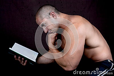 Young attractive male bodybuilder reading the book Stock Photo