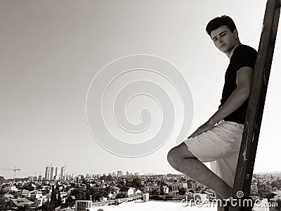 Young attractive man posing in front of camera on the roof of a residential building standing on a ladder Stock Photo