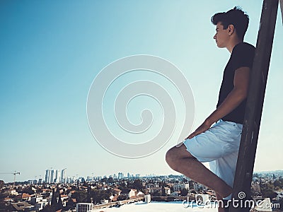 Young attractive man posing in front of camera on the roof of a residential building standing on a ladder Stock Photo