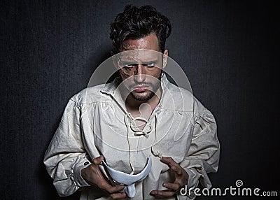 Young attractive man with scars from burns, holding a white theater like mask Stock Photo