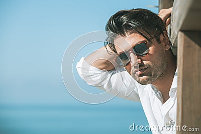 Young attractive man with sunglasses looking out over the sea during the summer. Stock Photo