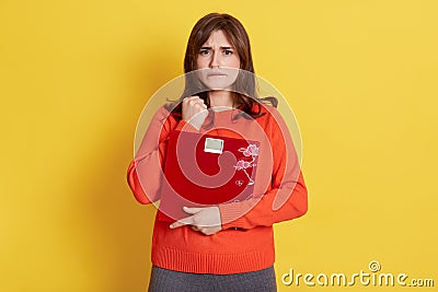 Young attractive model holding scales in hands being upset keeping fist near face and bites lip need to loose weight does not Stock Photo