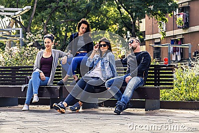 Young and attractive people are sitting on a bench in ghetto street. Stock Photo
