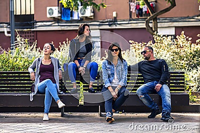 Young and attractive people are sitting on a bench in ghetto street. Stock Photo