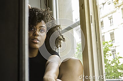 Young attractive sensual black woman sitting near the window looking at the camera Stock Photo