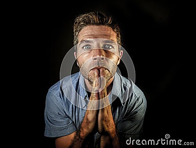 Young attractive stressed man with hands palms together praying and wishing success to come looking concentrated hoping for good l Stock Photo