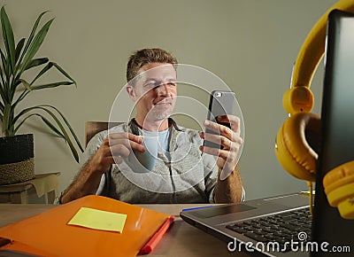 Young attractive and successful self employed business man using mobile phone sending text working at modern home office hispter s Stock Photo