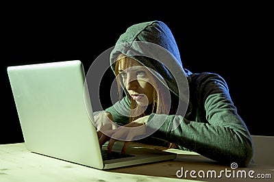 Young attractive teen woman wearing hood on hacking laptop computer cybercrime cyber crime concept Stock Photo