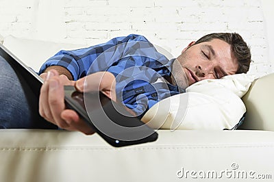 Young attractive tired and overworked falling asleep at home couch with mobile phone and digital tablet pad Stock Photo