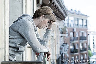 Young attractive unhappy depressed lonely woman looking down hopeless on the balcony at home Stock Photo