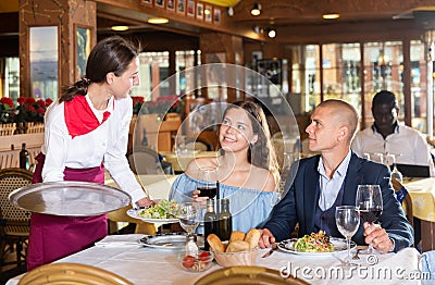 Young attractive waitress brings an order to couple Stock Photo