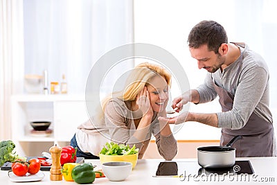 Young attractive woman give food to her husband to taste Stock Photo