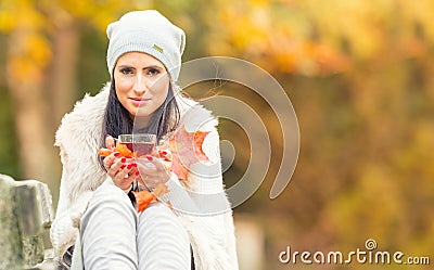 Young attractive woman holding in hand hot red tea. Relaxing in autumn nature with hot tea Stock Photo