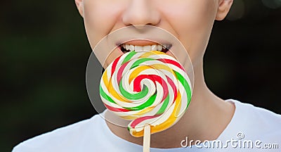 Young attractive woman is holding a multicolored, round lollipop near the mouth Stock Photo