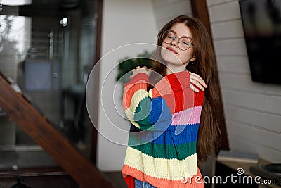 Young attractive woman hugging herself in a home interior, dressed in a warm sweater Stock Photo