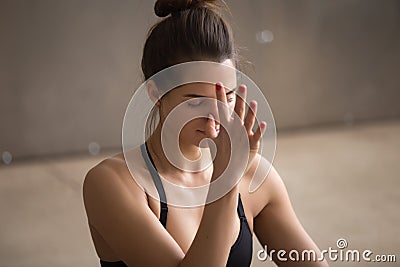 Young attractive woman making nadi shodhana pranayama, grey stud Stock Photo