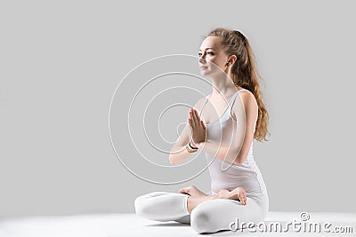 Young attractive woman in Padmasana pose with namaste, grey stud Stock Photo