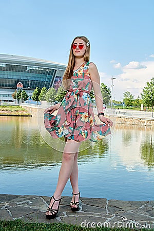 Young attractive woman. Red sunglasses, color dress. Girl`s portrait. Football stadium background. Stock Photo